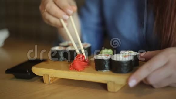 漂亮的白人商务女性戴着红色头发和眼镜在餐馆里用筷子吃日本卷视频的预览图