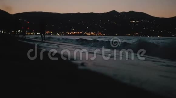 黄昏时海滩上的家庭剪影傍晚时分城市的灯火通明爸爸妈妈和女儿视频的预览图
