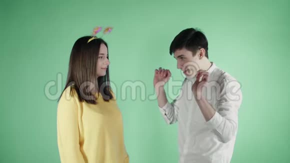 年轻的女人和男人在绿色的背景上用五颜六色的纸屑跳舞视频的预览图