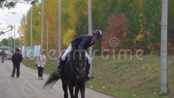 一个年轻的女人骑着一匹黑白马服的马慢慢地骑着一匹马马术比赛之间的中断视频的预览图