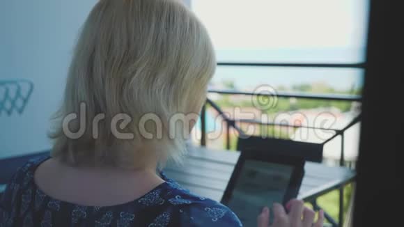 年轻女孩用平板电脑坐在家里的沙发上在网上商店里找东西购物社交媒体视频的预览图