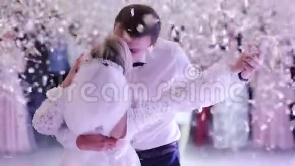 年轻美丽的新娘和新郎在婚礼上跳舞第一支舞被五彩纸屑笼罩视频的预览图