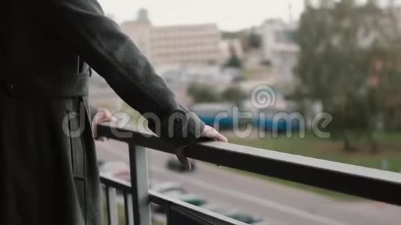 近景的年轻美女站在阳台上看着城市和道路微笑着视频的预览图