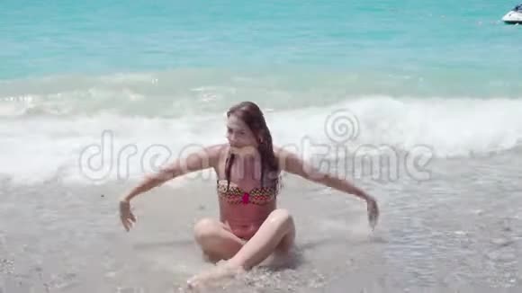 漂亮的女孩穿着泳衣手举起来在海水中飞溅4K视频的预览图