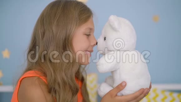 可爱的女孩抱着泰迪熊坐在家里的床上视频的预览图