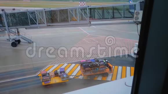 带有行李的行李牵引车通过机场空中桥附近的一个人行横道视频的预览图