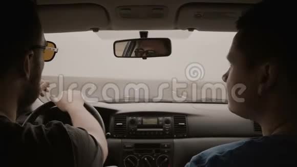 从车里看两个人开车穿过乡村公路戴墨镜的男人开车和朋友聊天视频的预览图