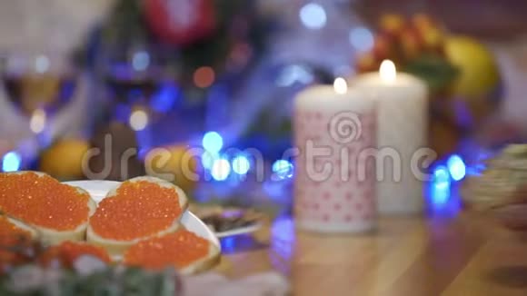 手放在节日的桌子上奥利维放在蜡烛和圣诞树的背景上视频的预览图
