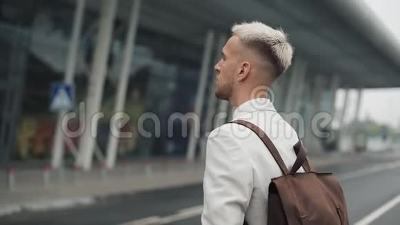 在工作的商人英俊的年轻人穿着白色衬衫带着背包去机场看着钟旅费视频的预览图