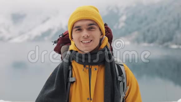 一个年轻的徒步旅行者的肖像背包站在大自然的冬天放弃拇指美丽美丽视频的预览图