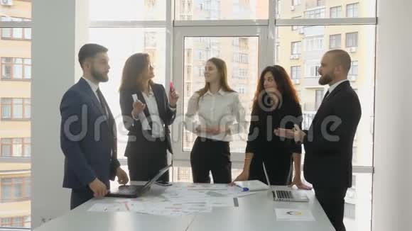 办公室工作人员一家大公司的雇员两名青年男子和三名青年妇女站在一张有文件的桌子旁视频的预览图