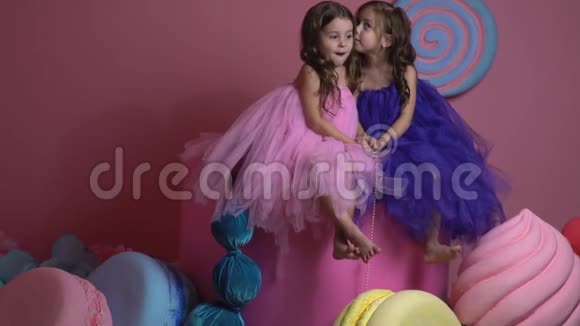 女孩们坐在玩具糖果和蛋糕中间一个人在耳边低语着其他的东西视频的预览图