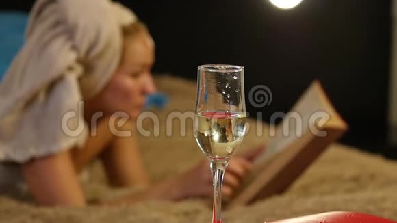 特写香槟流入玻璃杯漂亮的小女孩舒服地躺在床上看书慢动作视频的预览图