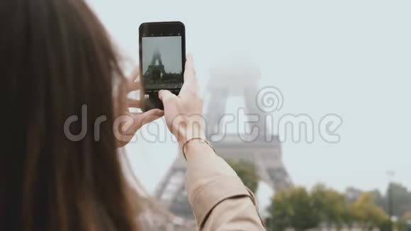 年轻漂亮的女人在法国巴黎散步在智能手机或手机上雾中拍摄埃菲尔铁塔的照片视频的预览图