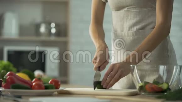 女人一边切黄瓜一边在家里的厨房做沙拉视频的预览图
