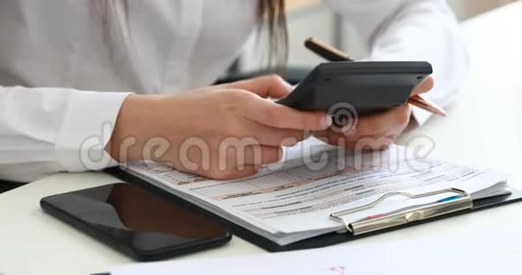 女人手里拿着计算器和现代办公室的文件视频的预览图