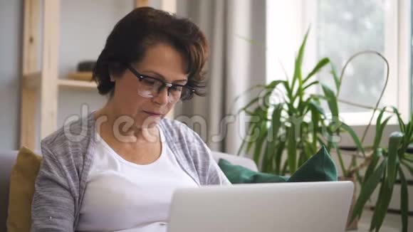棕色头发的成熟女人戴着眼镜坐在沙发旁视频的预览图