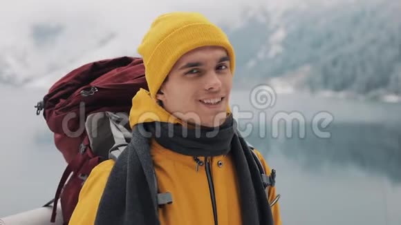 一个年轻的徒步旅行者的肖像背包站在大自然的冬天放弃拇指美丽美丽视频的预览图