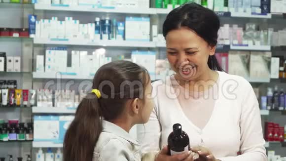 一个微笑的女人和她的女儿在药房里选择一些东西视频的预览图