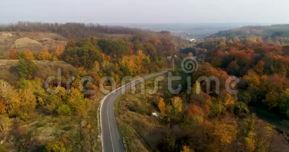 在乡间道路上驾驶汽车穿过森林的鸟瞰图美丽的风景空旷的乡村道路红色的树木视频的预览图