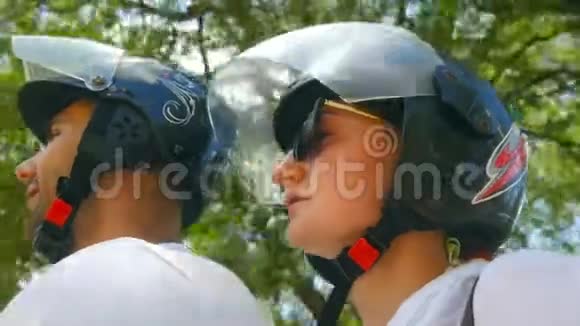 戴着头盔的年轻夫妇沿着热带乡村道路骑着滑板车微笑的男人和女人开车旅行视频的预览图