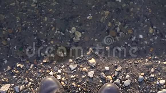 一个穿着鞋子的人站在河边或水坑附近鞋子在水边视频的预览图