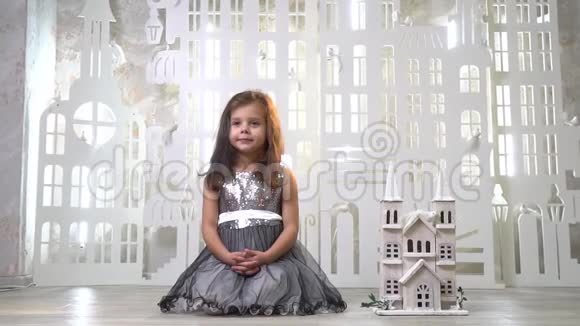一个穿着亮片连衣裙的女孩坐在玩具锁旁边的房间里背景是墙上的一只玩具鸟动作缓慢视频的预览图