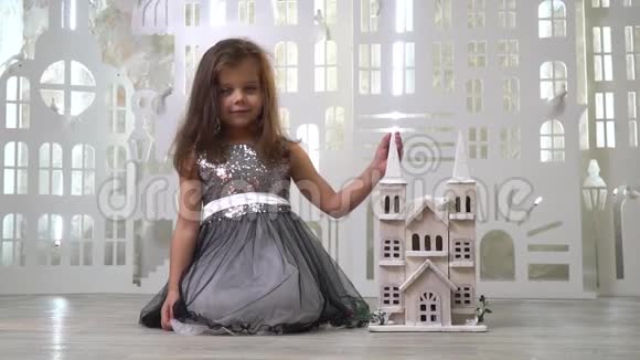 一个穿着灰色裙子的善良女孩带着闪闪发光的微笑手里拿着一个玩具宫殿慢动作视频的预览图