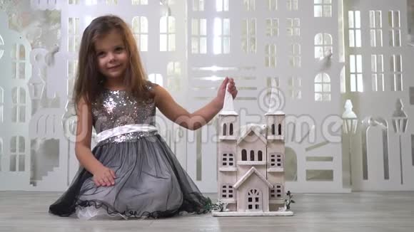 穿着闪闪发光的浅黑色小女孩坐在玩具宫殿和微笑慢动作视频的预览图