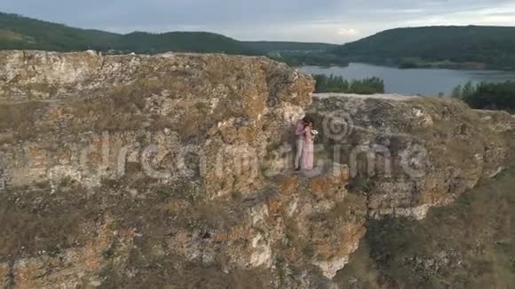 年轻夫妇站在海边的悬崖和岩石上的鸟瞰图视频的预览图