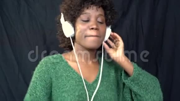 穿着绿色毛衣的非裔美国人用智能手机耳机听音乐慢动作视频的预览图