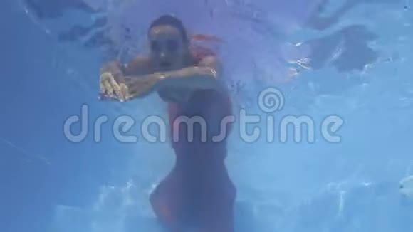 化妆的年轻女子在水下游泳穿着红色连衣裙4k视频的预览图