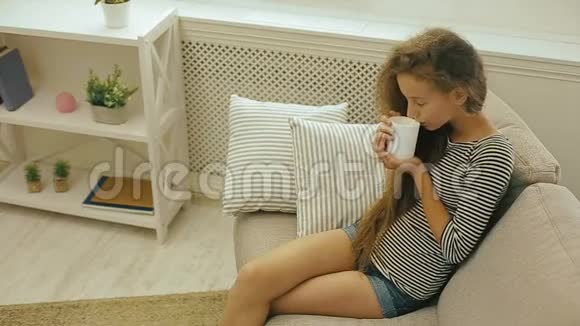 坐在沙发上喝着新鲜牛奶的小女孩视频的预览图