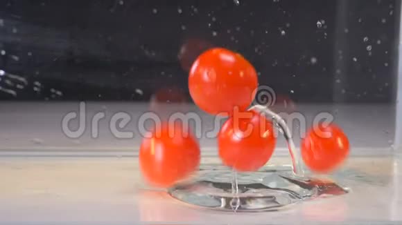 一堆西红柿掉进一个装有少量水的玻璃容器里的过程视频的预览图