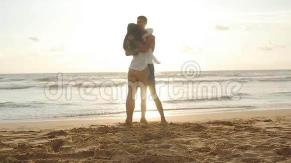 快乐的一对夫妻在日落时在海边亲吻和拥抱年轻人和女人相爱在一起玩视频的预览图