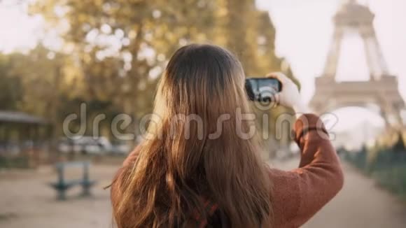 年轻女性在智能手机上拍照的背面视图青少年游客在法国巴黎探索埃菲尔铁塔视频的预览图