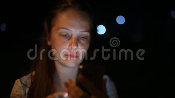 生活方式的女人手里拿着一部手机在夜城与社交网络上的朋友交流视频的预览图