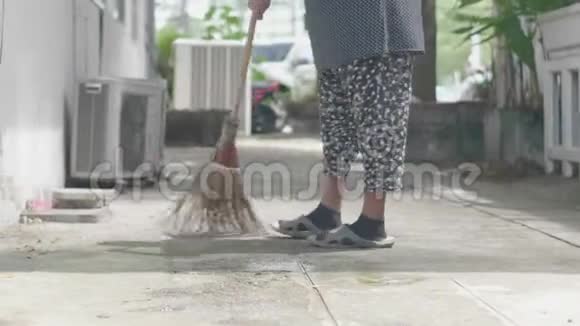 不明身份的女人在公园里用扫帚扫树叶特写视频的预览图