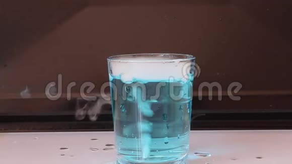 在一杯蓝色的水中干冰在白色的地板上产生白色的烟雾背景是黑色的视频的预览图