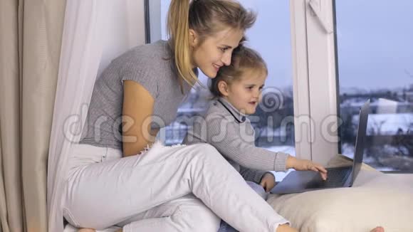 可爱的女孩和她的母亲使用笔记本电脑视频的预览图