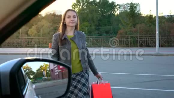 女人把购物袋放在汽车座椅上坐在其中打算开车离开视频的预览图