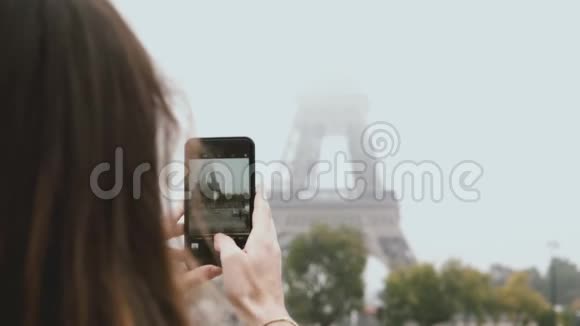 在埃菲尔铁塔的智能手机上拍照的年轻女子的特写镜头在法国巴黎使用手机的女性视频的预览图