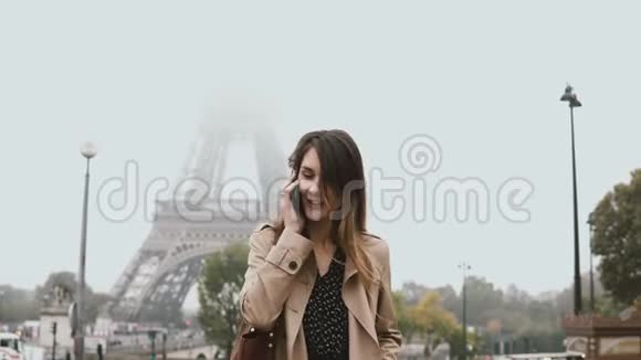 年轻时尚的女人走在法国巴黎埃菲尔铁塔附近和朋友用手机交谈视频的预览图