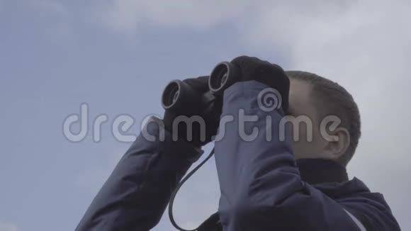 年轻的旅行者用望远镜看天空云背景视频的预览图