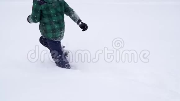 美丽快乐的学龄前男孩跑过深深的雪堆视频的预览图