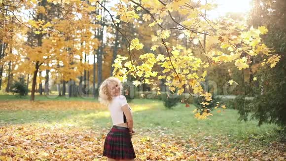 美丽的金发女人摸着卷发走在秋天的公园里视频的预览图