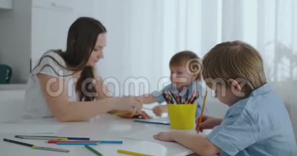 两个男孩的孩子和他的母亲坐在厨房里画画家庭幸福视频的预览图