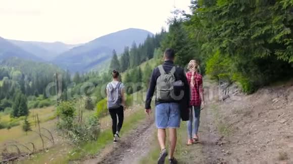 三个游客在森林附近的山路上散步视频的预览图