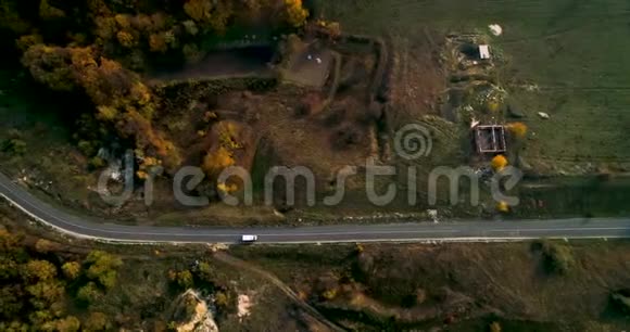 在乡间道路上驾驶汽车穿过森林的鸟瞰图美丽的风景空旷的乡村道路红色的树木视频的预览图