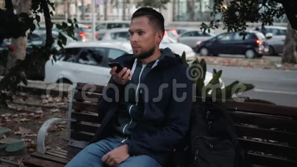 休闲快乐的人坐在公园的长凳上游客使用语音识别人工语音辅助音频视频的预览图